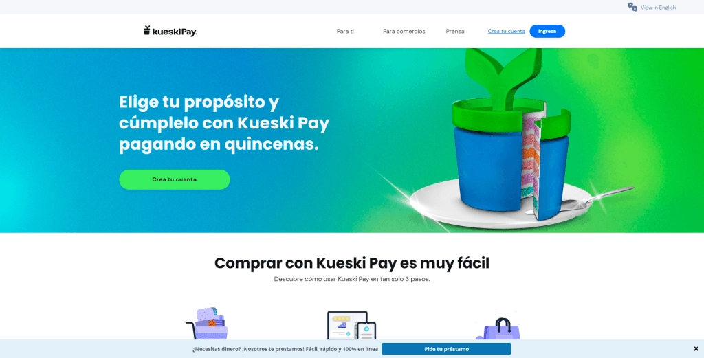 Imagen de la página principal de Kueski Pay, que destaca la opción de pagar en quincenas. Muestra un diseño colorido con un fondo azul y verde, y un gráfico de un pastel en una maceta, simbolizando el cumplimiento de propósitos. Incluye un botón para crear una cuenta y un mensaje sobre la facilidad de uso de la plataforma.