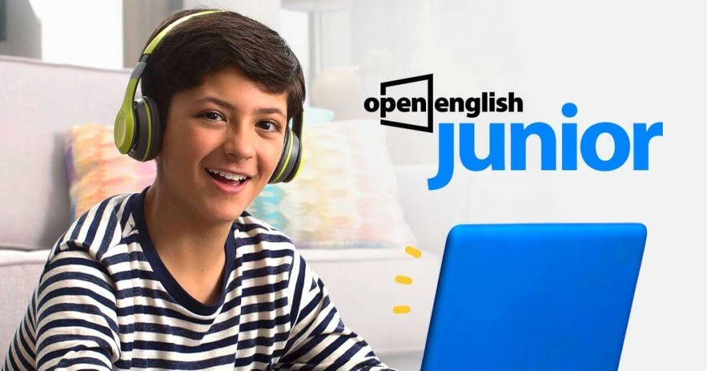 Niño sonriente usando auriculares mientras estudia en una computadora portátil azul, promoviendo el programa Open English Junior.