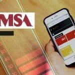 Imagen que muestra un teléfono móvil en una mano, con la pantalla enfocada en la aplicación KPRS de FEMSA, sobre un fondo de mesa de madera. El logo de FEMSA se encuentra en la parte superior izquierda, mientras que la pantalla del dispositivo muestra varias opciones como 